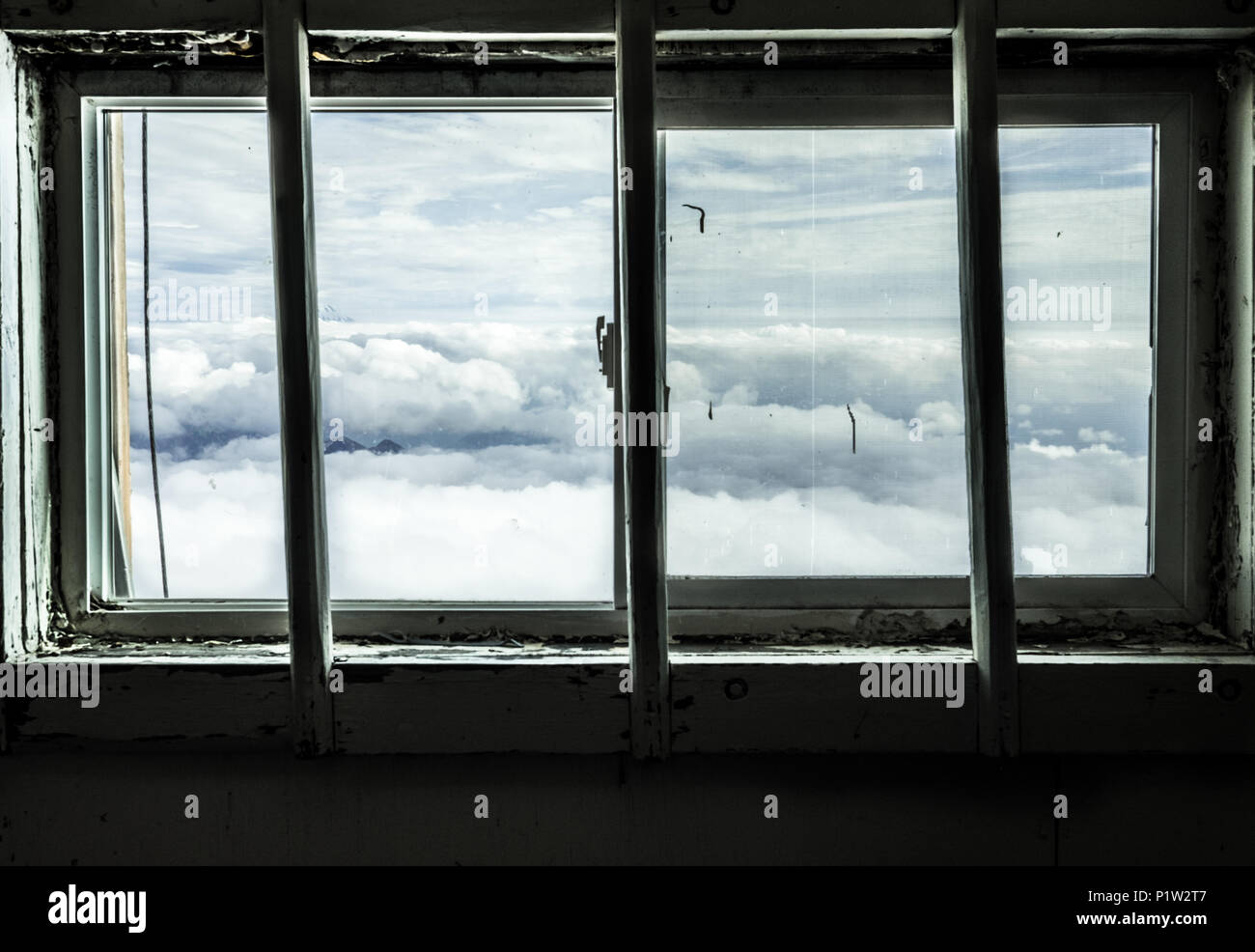 Decrepit old window with a view of a sea of clouds Stock Photo
