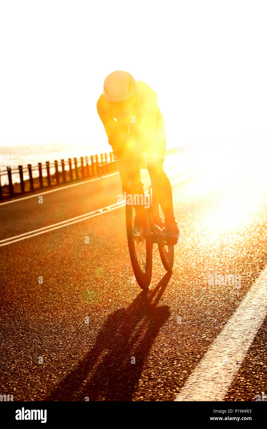 stunning early morning shot of a triathlete riding their bike bicycle on the open road during an ironman competition between Cairns and Port Douglas Stock Photo
