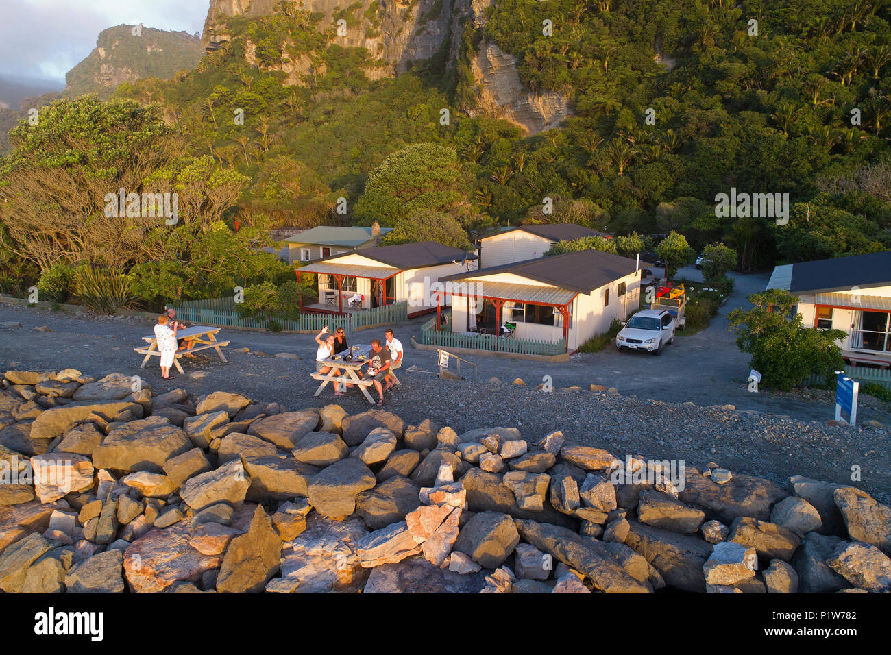 People at picnic table on sea wall, Punakaiki, West Coast, South Island, New Zealand - drone aerial Stock Photo
