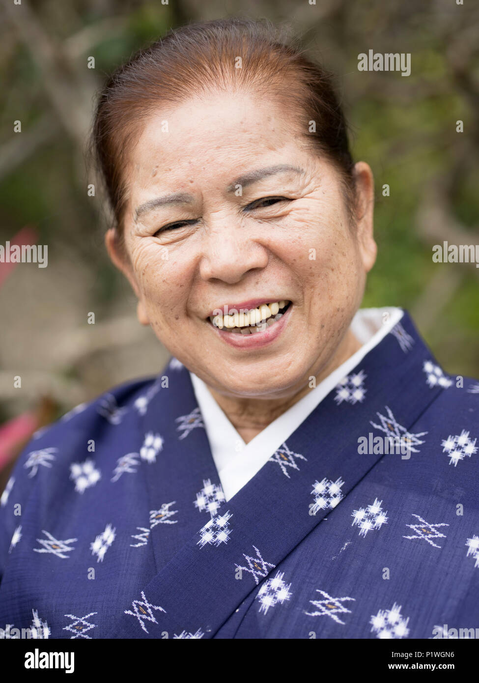 Smiling elderly Okinawan woman in traditional lightweight summer kimono at Ryukyu Mura, Yomitan, Okinawa. Stock Photo