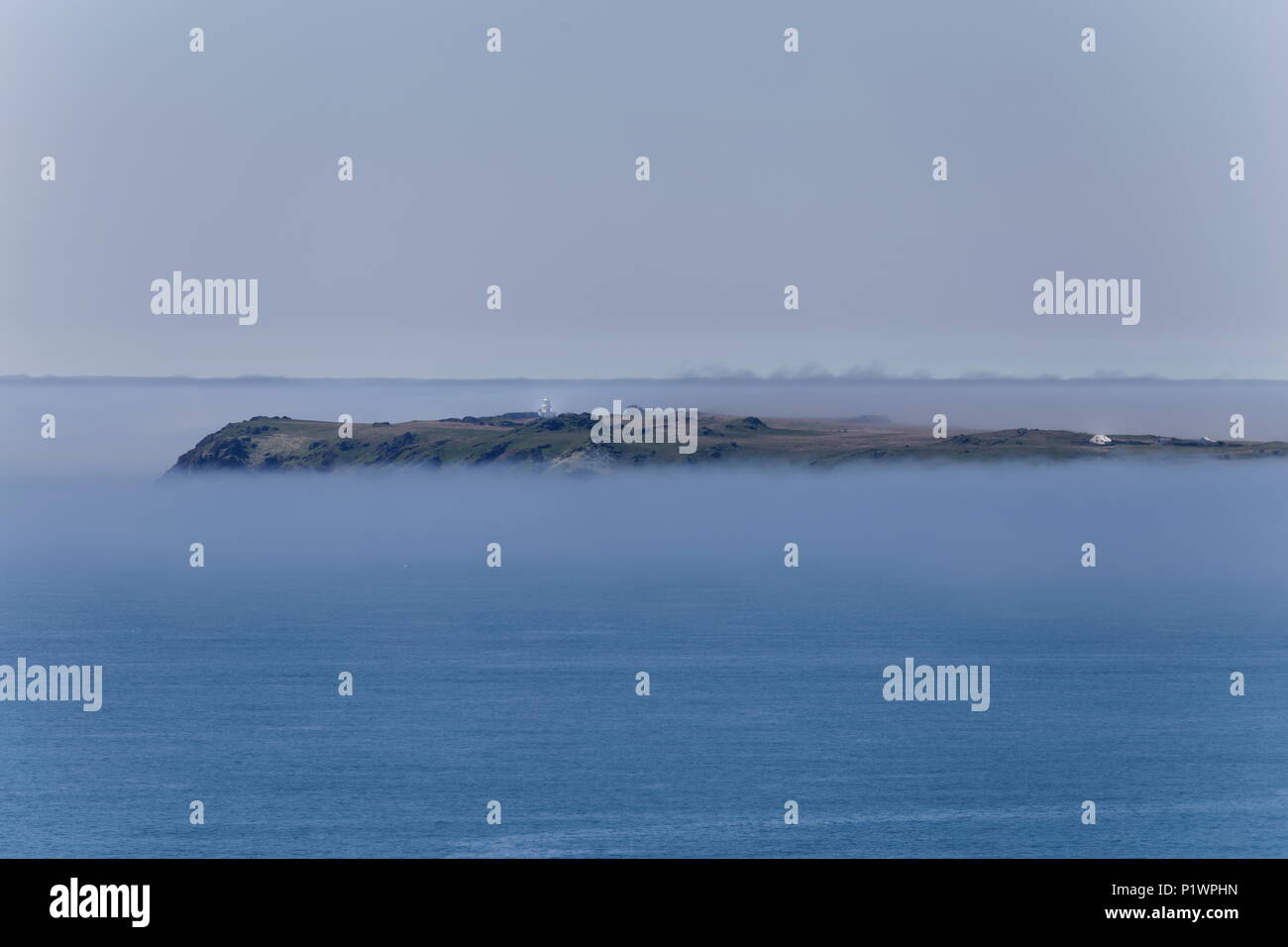 Looking over to Skokholm Island shrouded in sea mist Pembrokeshire Coast Path Pembrokeshire Wales Stock Photo