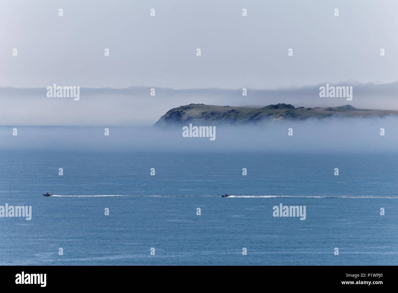 Two speed boats off  Skokholm Island shrouded in sea mist Pembrokeshire Coast Path Pembrokeshire Wales Stock Photo