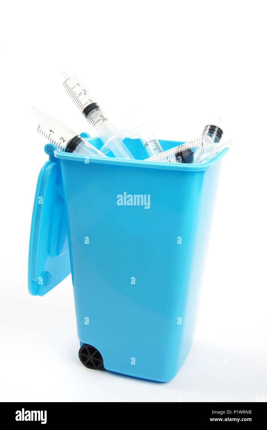 plastic medical syringes inside a blue rubbish bin with open lid on a white background Stock Photo