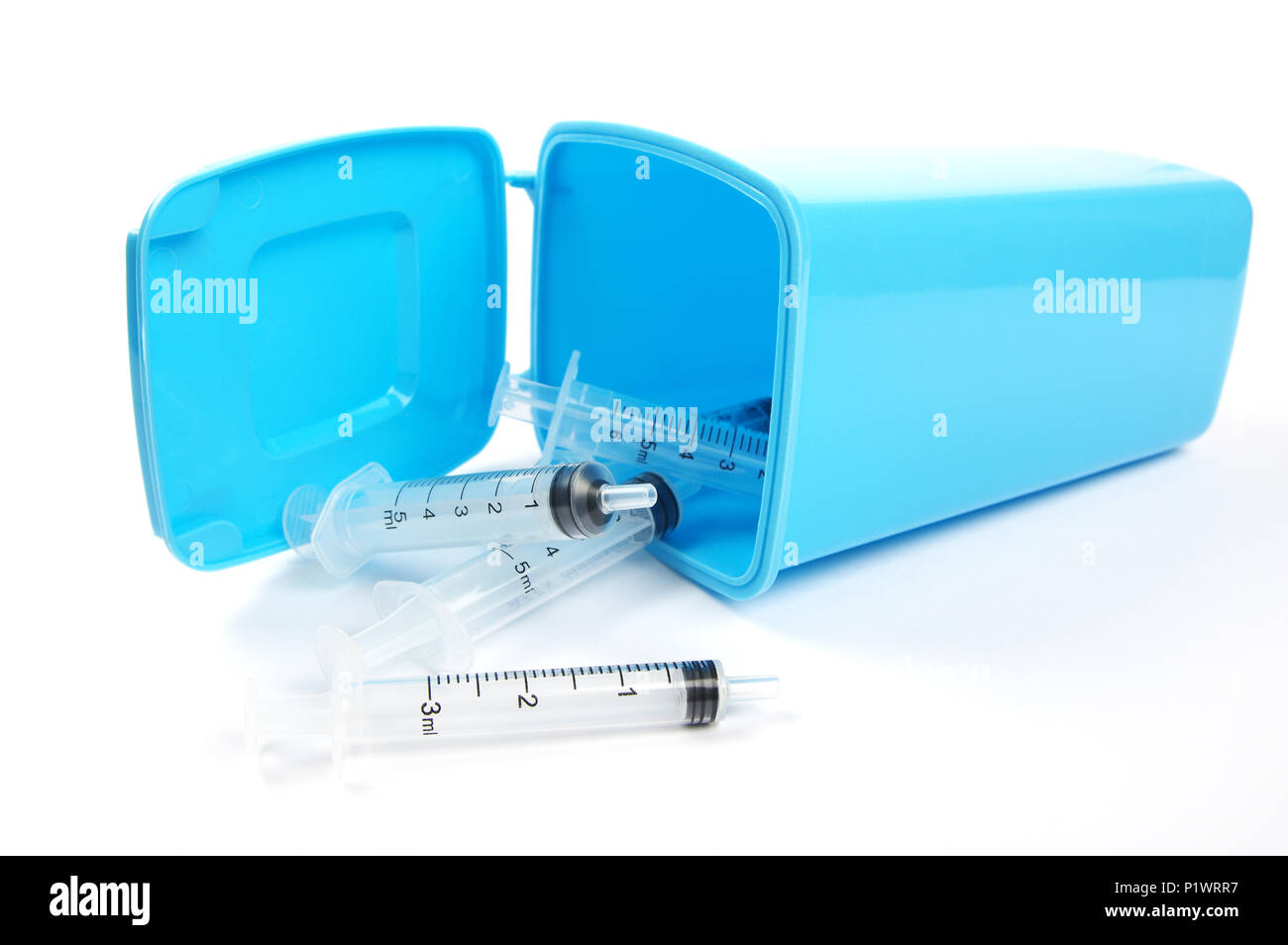 medical syringes spilling from a blue rubbish bin Stock Photo