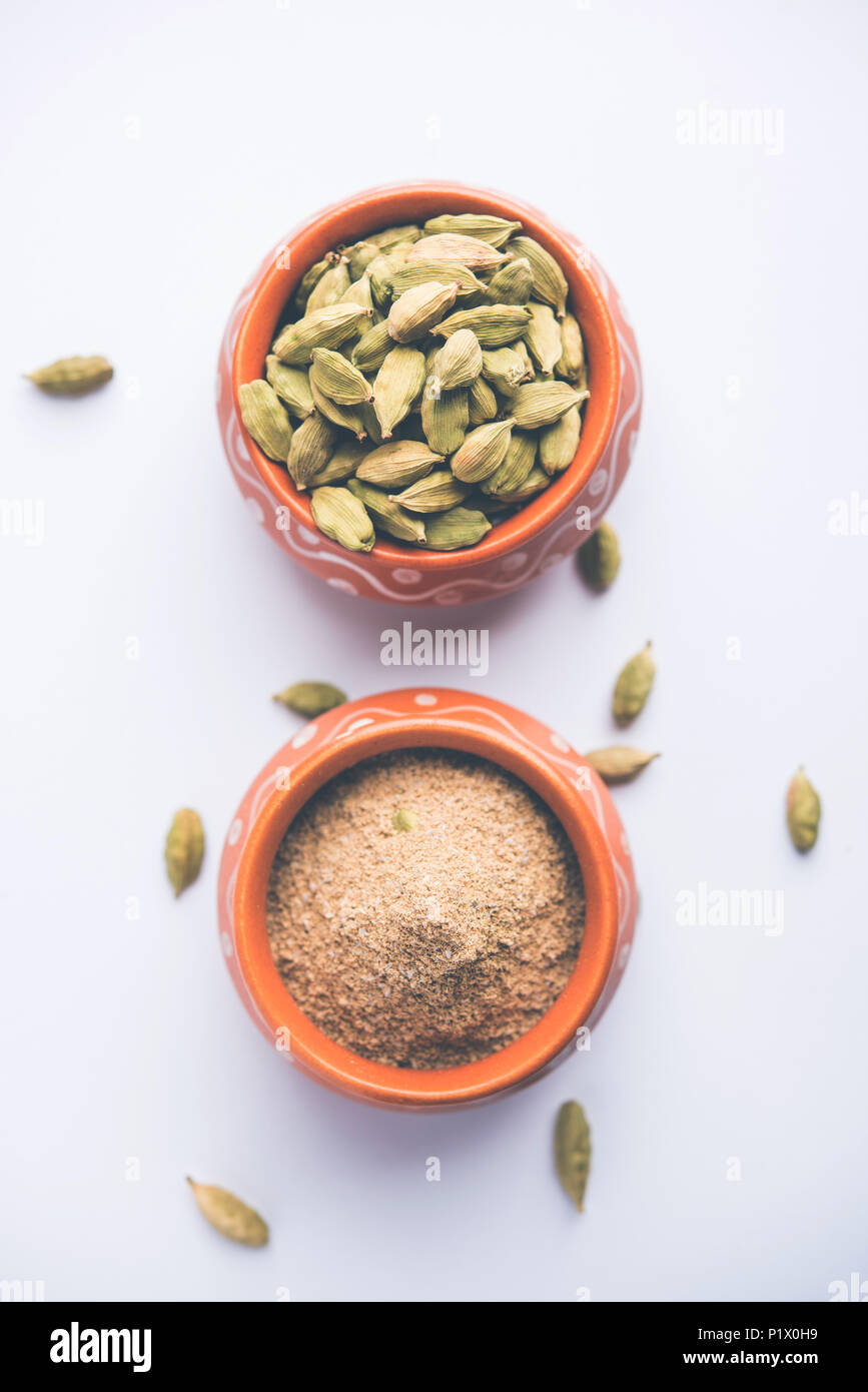 elaichi or Cardamom powder in bowl or heap over moody background with pods. selective focus Stock Photo