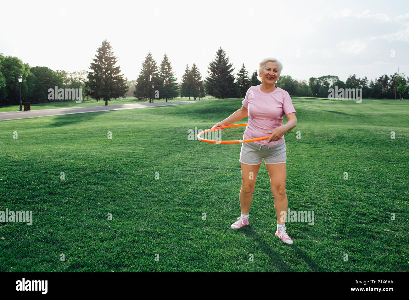 elderly woman does the exercise with hula hoops Stock Photo