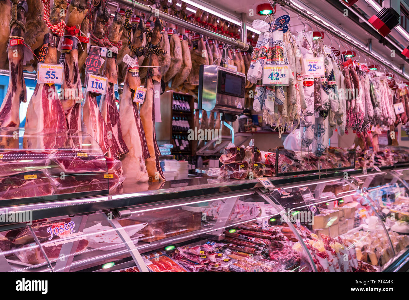 Spain, Barcelona - March 27, 2018: Boqueria market, jamon and sausages on the counter of the Spanish market Stock Photo