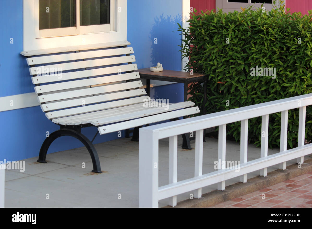 photo of white bench and table in front of blue house Stock Photo