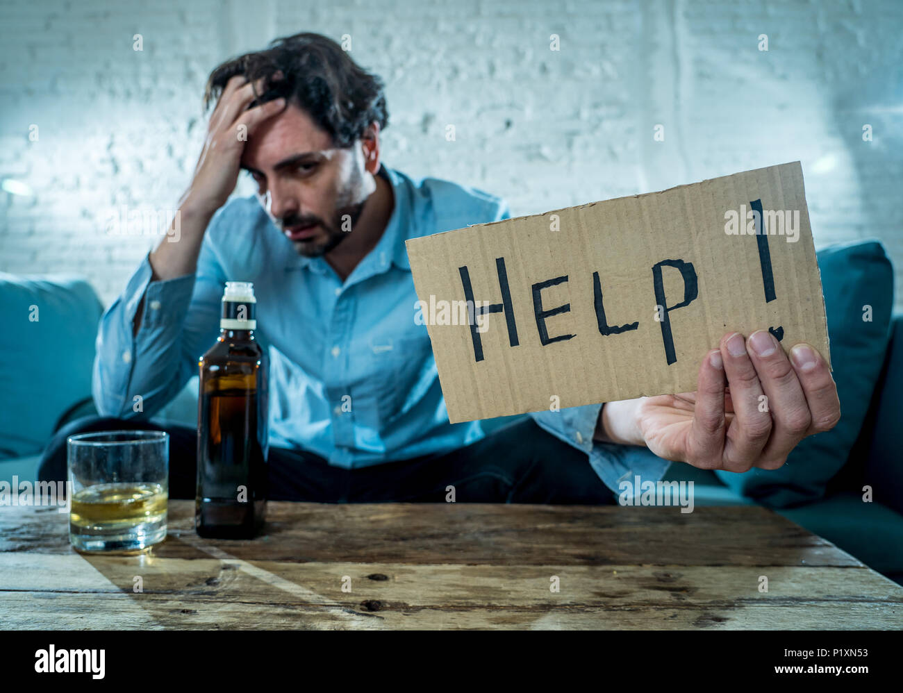 drunk alcoholic lain business man drinking whiskey from the bottle and glass depressed wasted and sad at home couch in alcohol abuse and alcoholism co Stock Photo