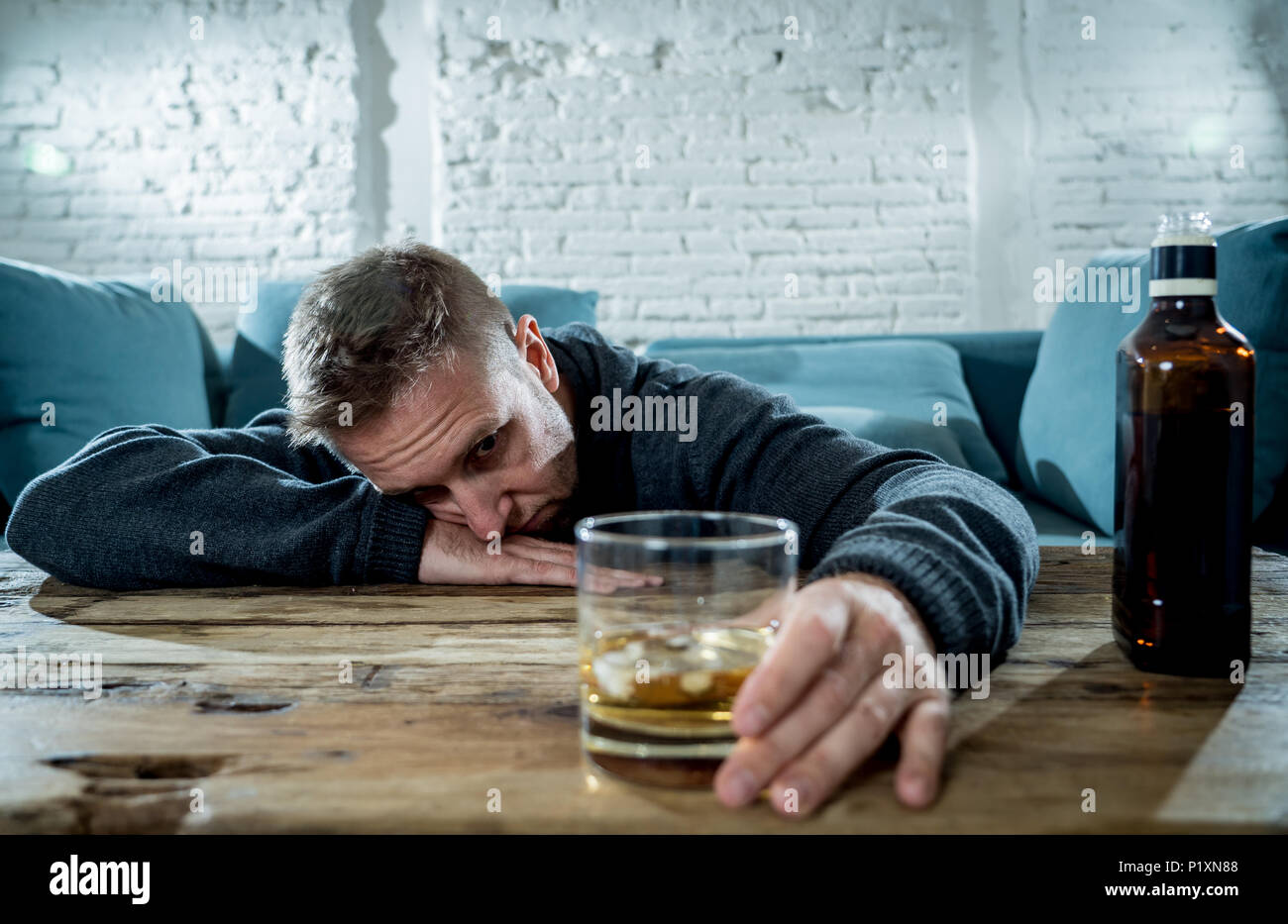 drunk alcoholic unemployed man drinking whiskey from the glass and bottle depressed wasted and sad at home couch in alcohol abuse and alcoholism conce Stock Photo - Alamy