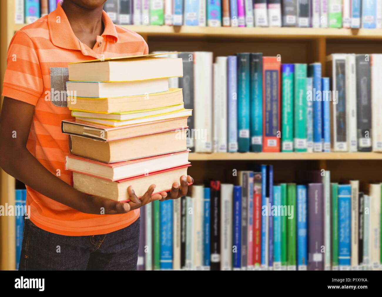 Boy holding books in education library Stock Photo - Alamy