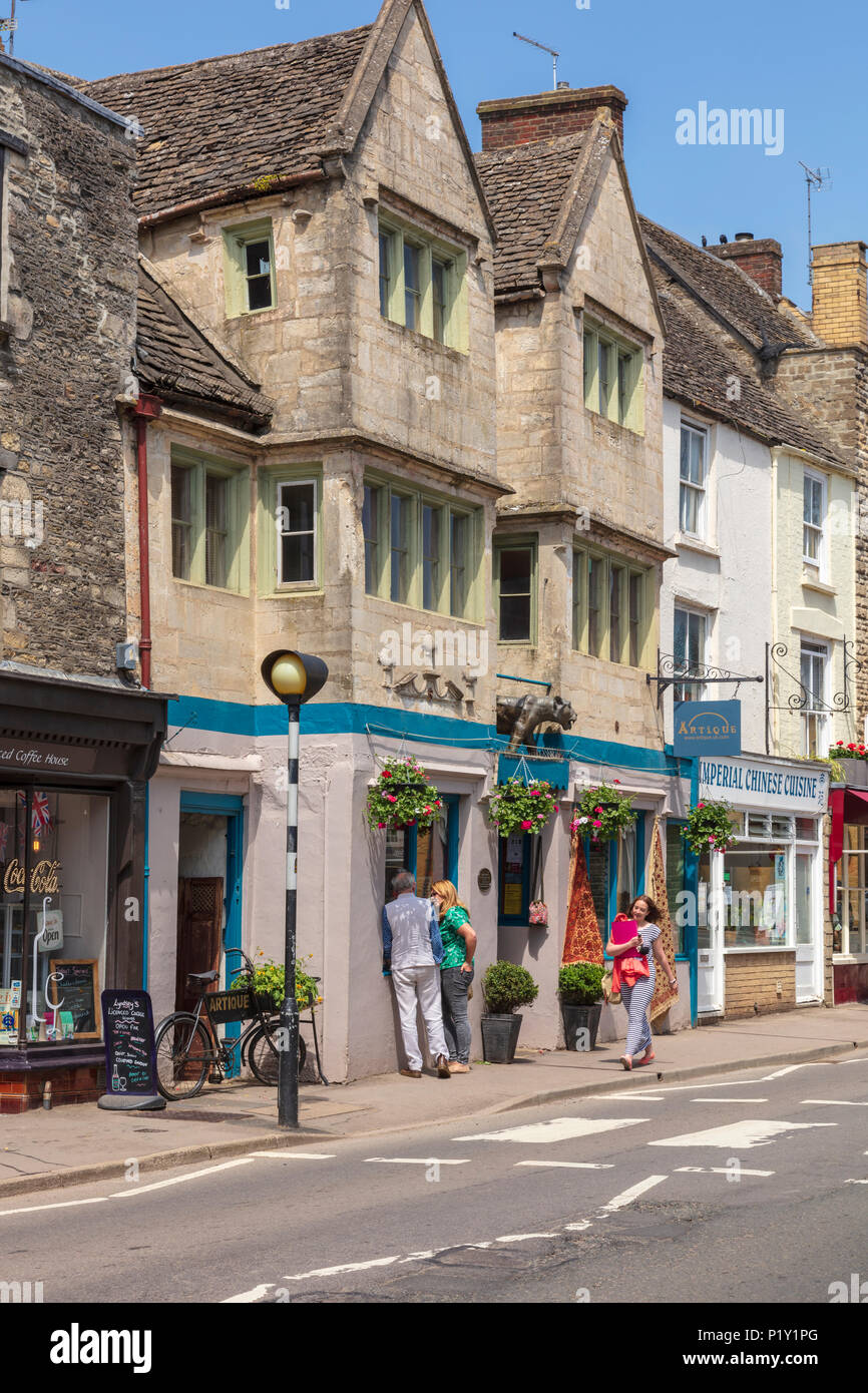 Attractive shops on Church Street, Tetbury, shoppers look in the