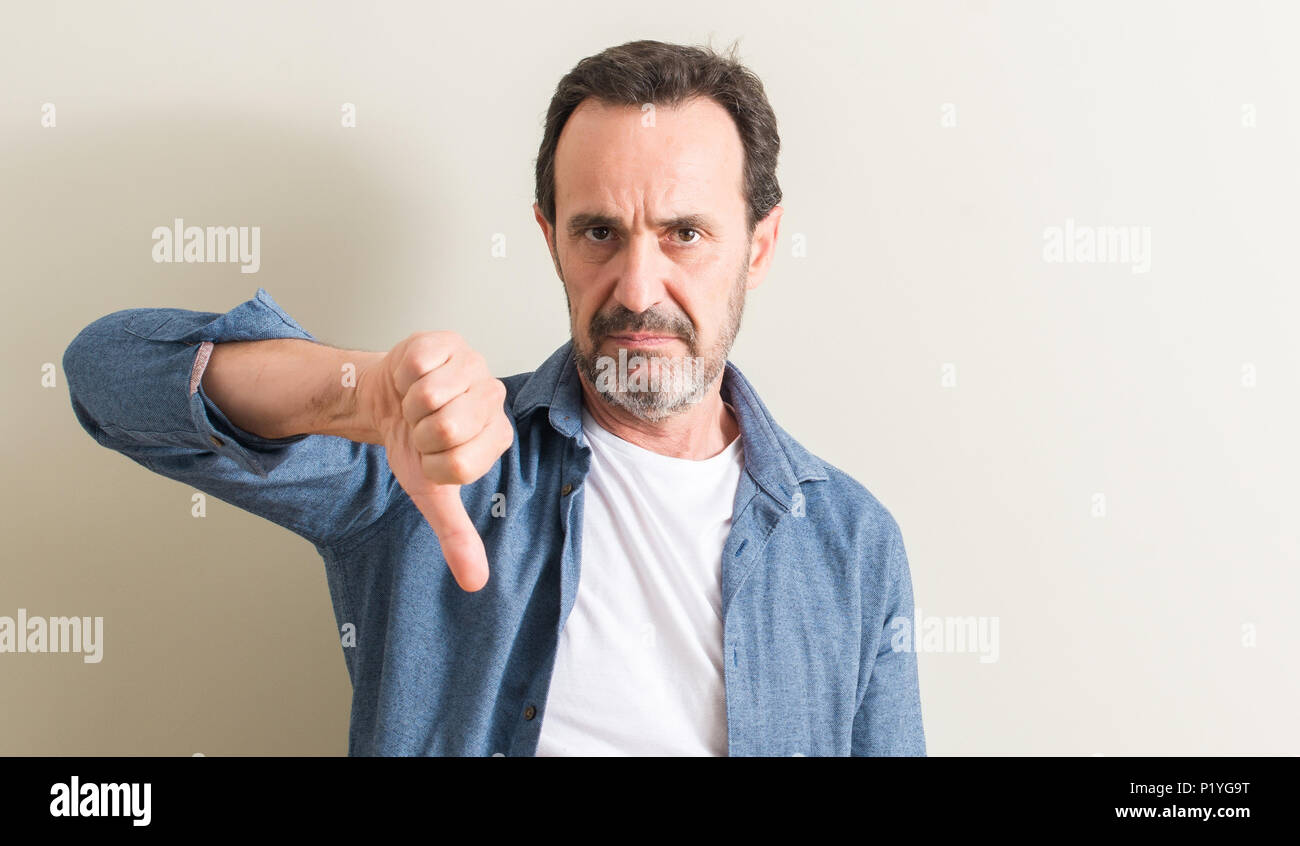 Senior man with angry face, negative sign showing dislike with thumbs ...