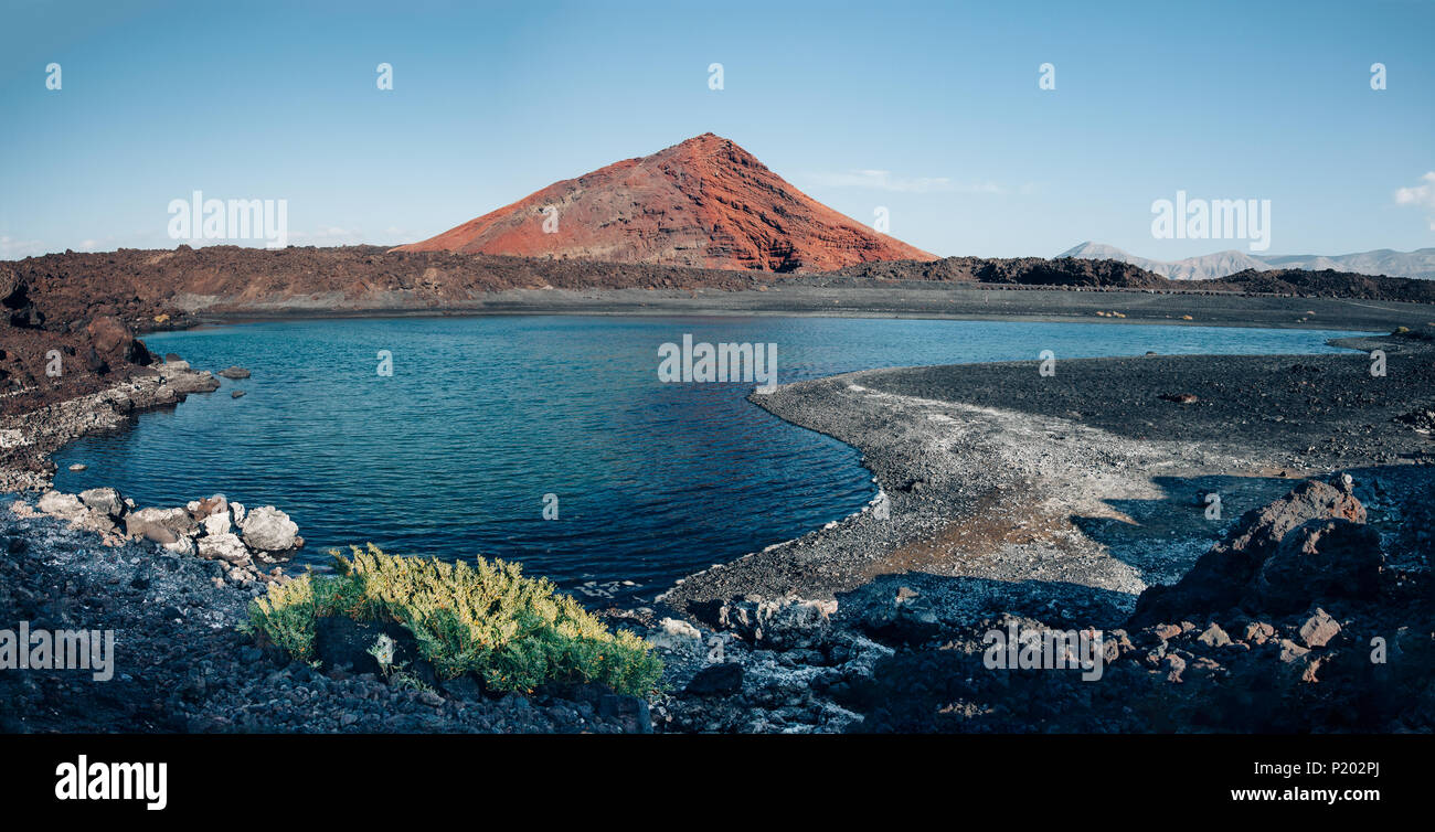 view of unique volcanic landscape in Lanzarote island. Black sand, lake and and mountain. Playa Bermeja. Travel destination. Nature back Stock Photo -