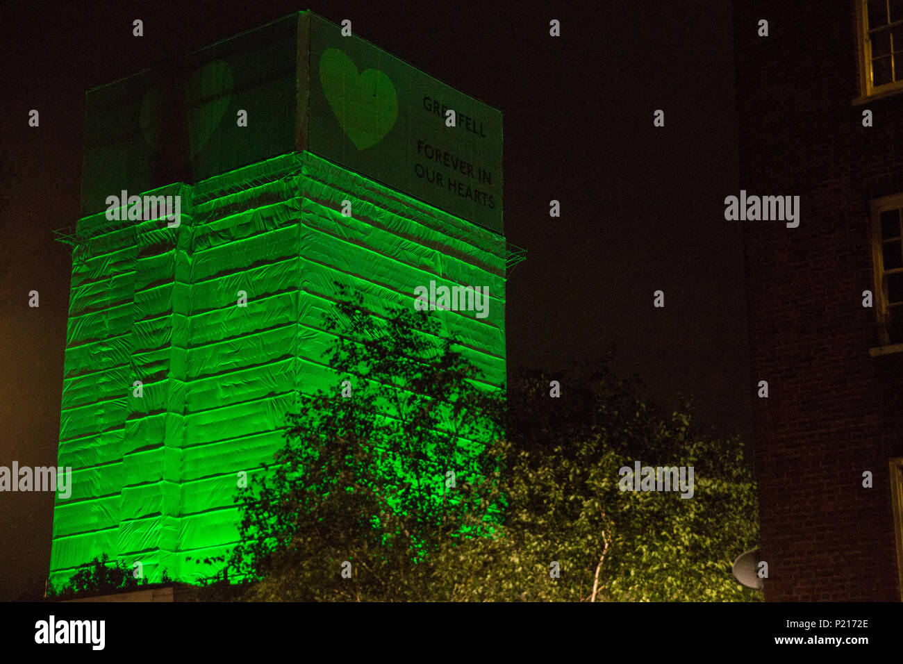 London, UK. 14th June, 2018. The Green for Grenfell illuminations are lit at the Grenfell Tower and the twelve closest tower blocks on the first anniversary of the fire in a display intended to 'shine a light' of love and solidarity for all those affected and to raise awareness of the plight of those still without new homes after one year. Green for Grenfell is a community-led initiative in collaboration with tenants' and residents' associations and Grenfell United. Credit: Mark Kerrison/Alamy Live News Stock Photo