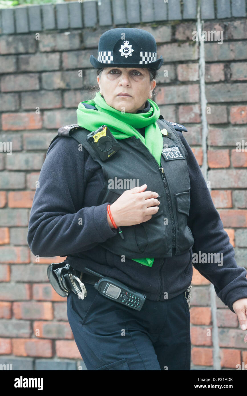 London UK. 14th June 2018. A police officer wearing a green scarfe  to mark the Grenfell anniversary a year after the fire  in West London which claimed the lives of 72 residents in the tower block.  A minute's silence will be observed nationally at midday to remember the victims of the Grenfell fire on 14 June 2017. Credit: amer ghazzal/Alamy Live News Stock Photo
