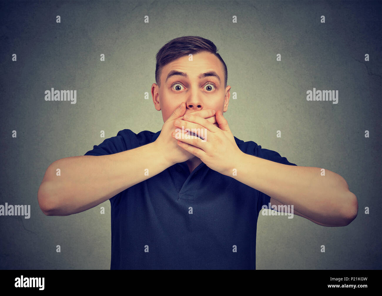 scared man with hands covering mouth anxiously looking at camera Stock Photo