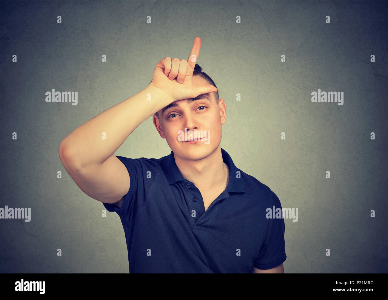 Young indifferent man looking at camera and showing loser sign. Stock Photo