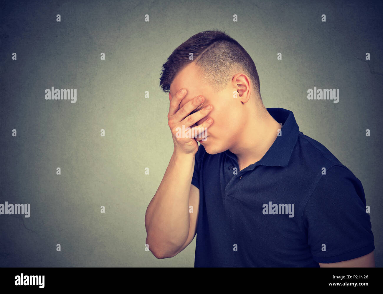 Sad depressed man with hand on face looking down Stock Photo