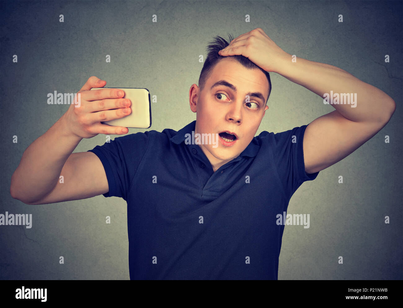 Portrait shocked man feeling head, surprised he is losing hair isolated on gray background. Negative facial expressions, emotion Stock Photo