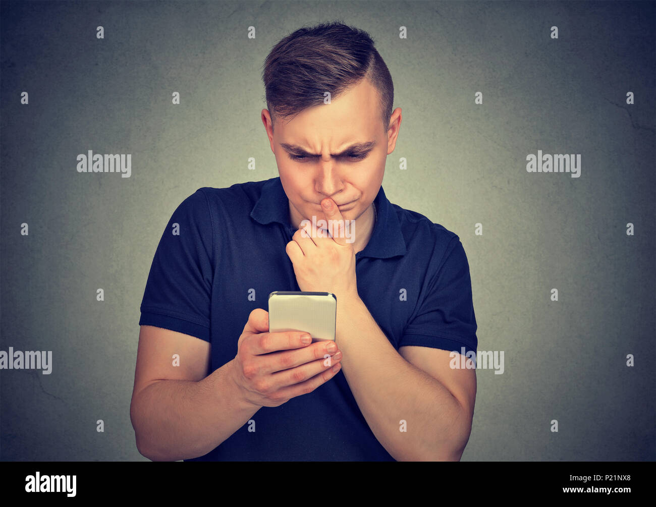 Clueless dumb guy having troubles with his smartphone. Complicated technology concept Stock Photo