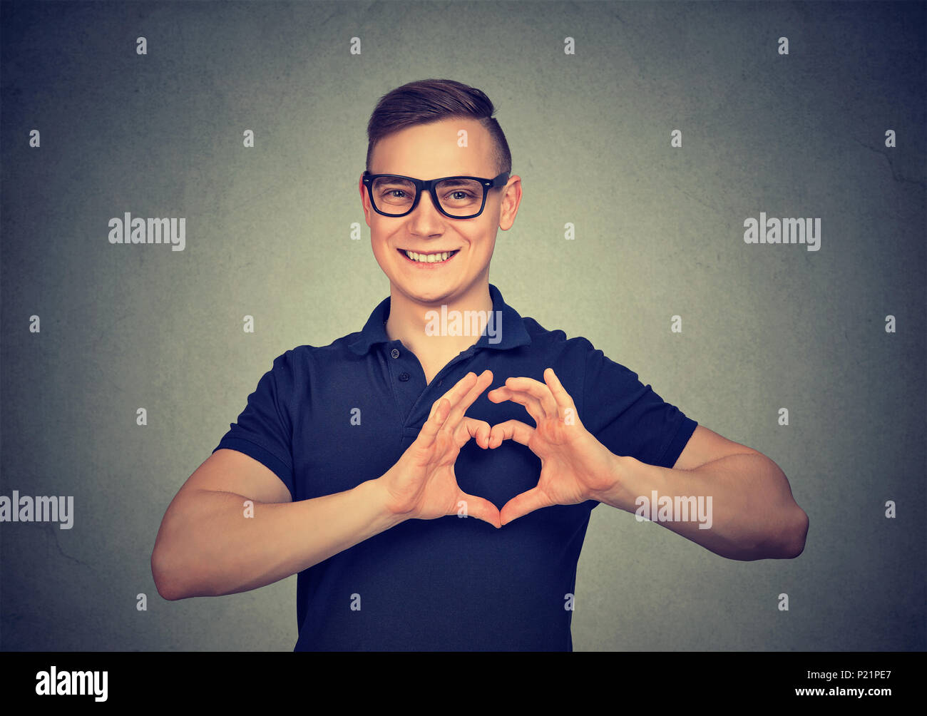 Portrait of happy handsome man in glasses making heart with fingers. Stock Photo