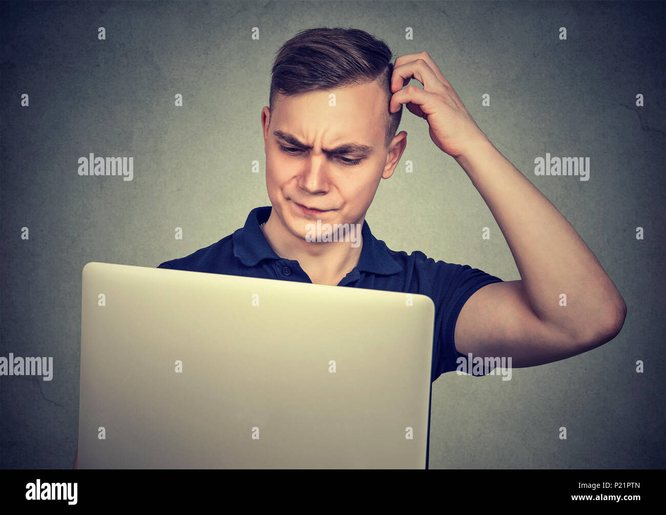 Young casual man looking perplexed while using laptop having difficulties with device. Stock Photo