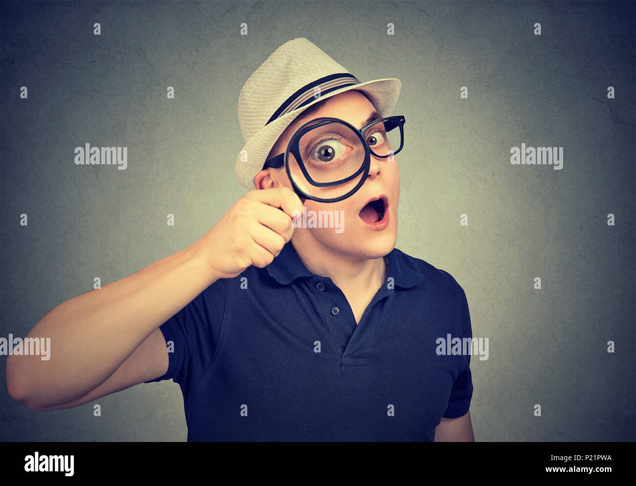 Portrait of a surprised investigator looking through magnifying glass Stock Photo