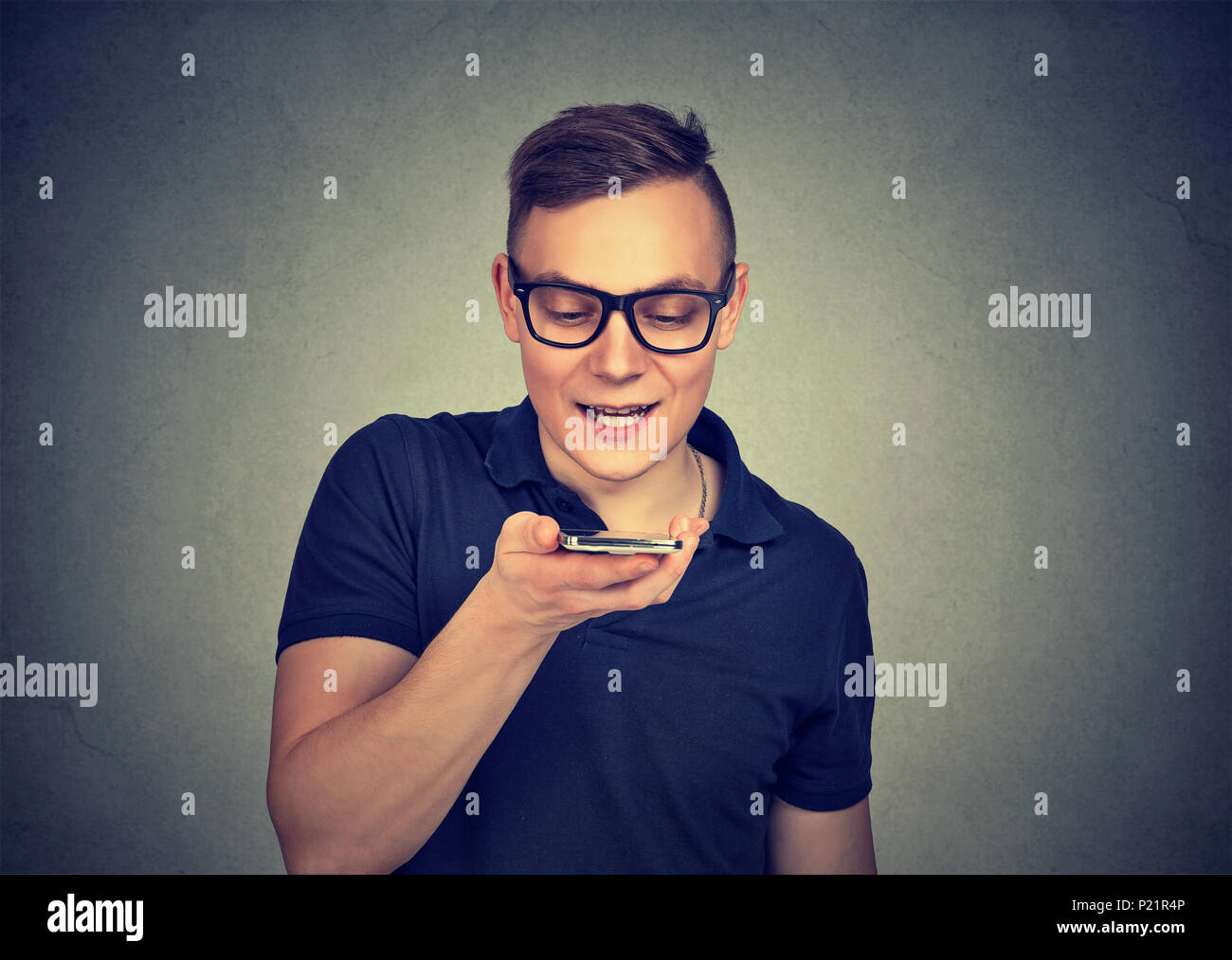 Man using a smart phone voice recognition function on line isolated on gray wall background Stock Photo