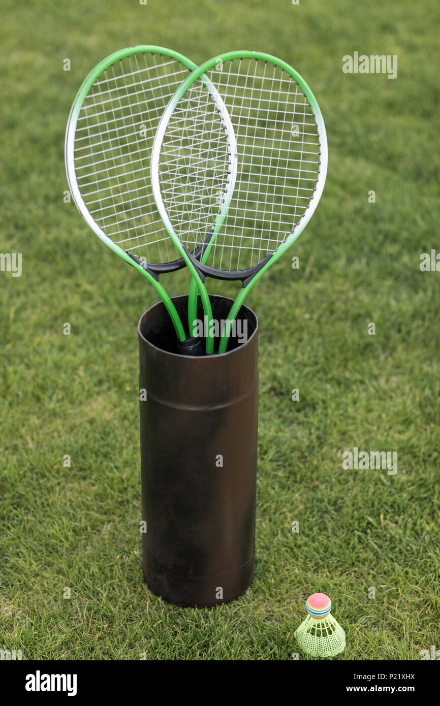 Two badminton racquets in container and shuttlecock on green grass ...