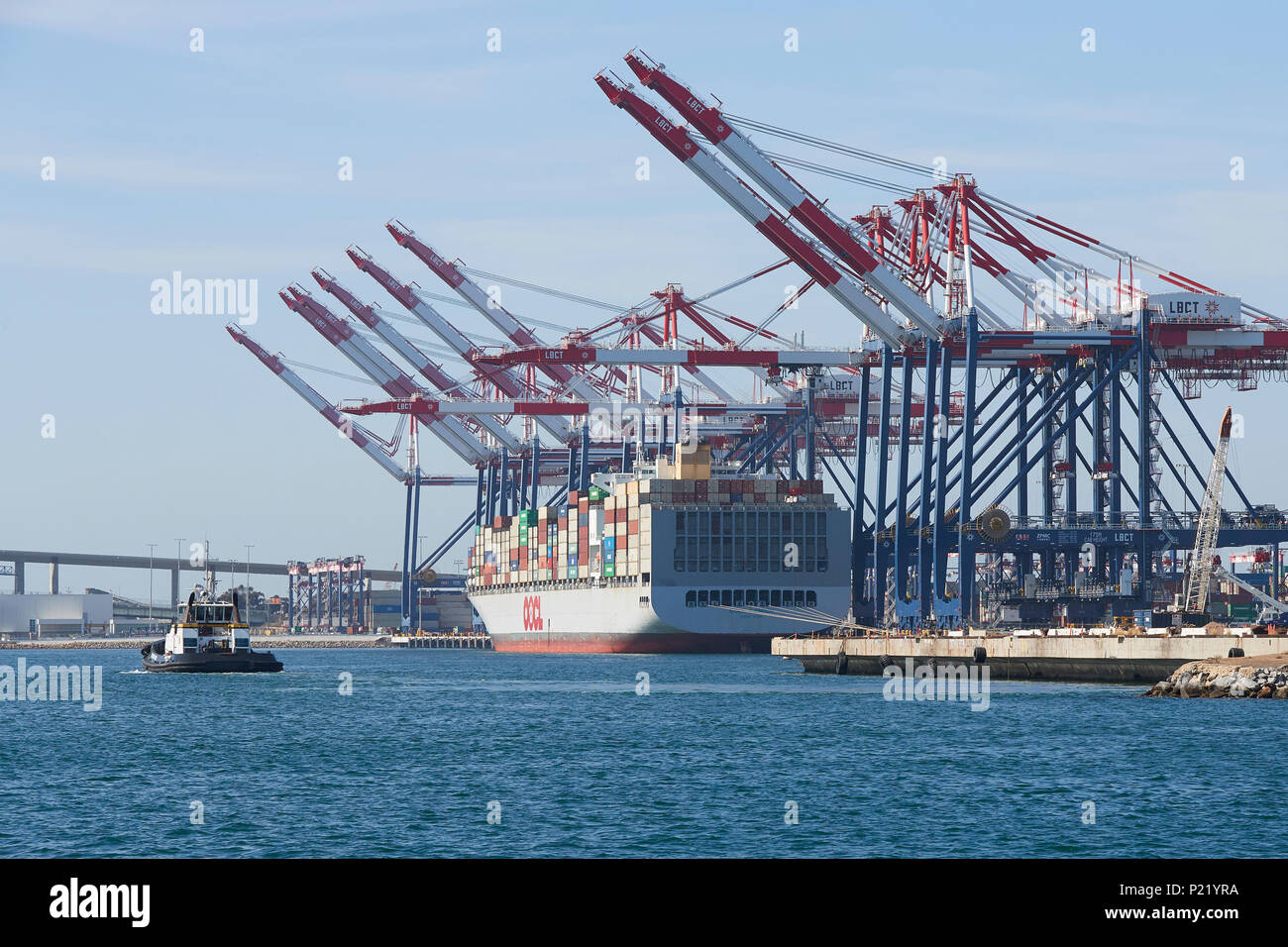 Container Ship, OOCL LONDON, About To Depart The Long Beach Container Terminal, A Tractor Tug Approaching The Ship. Port Of Long Beach, California Stock Photo