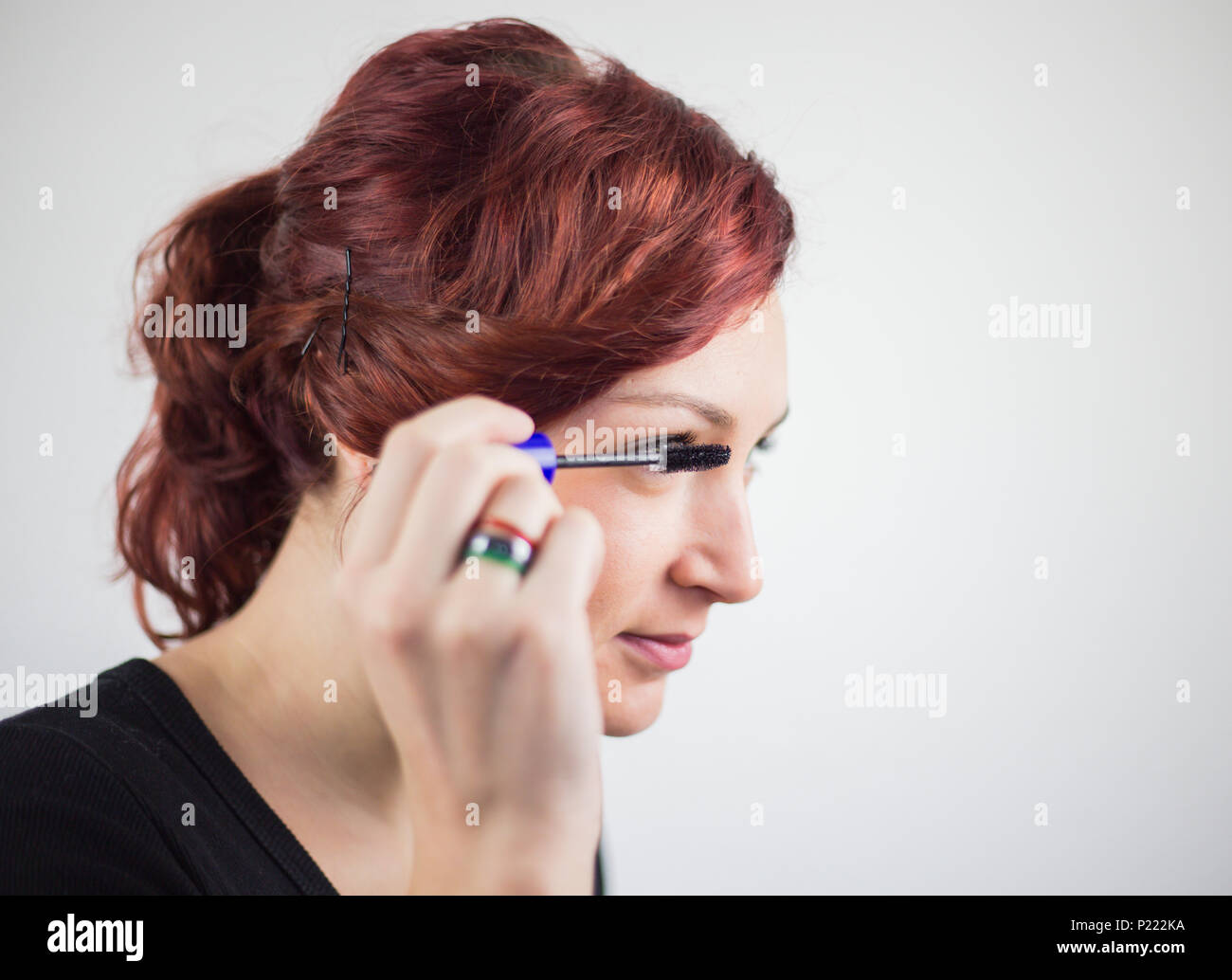 Young girl uses beauty care products, makeup, eye mascara, white