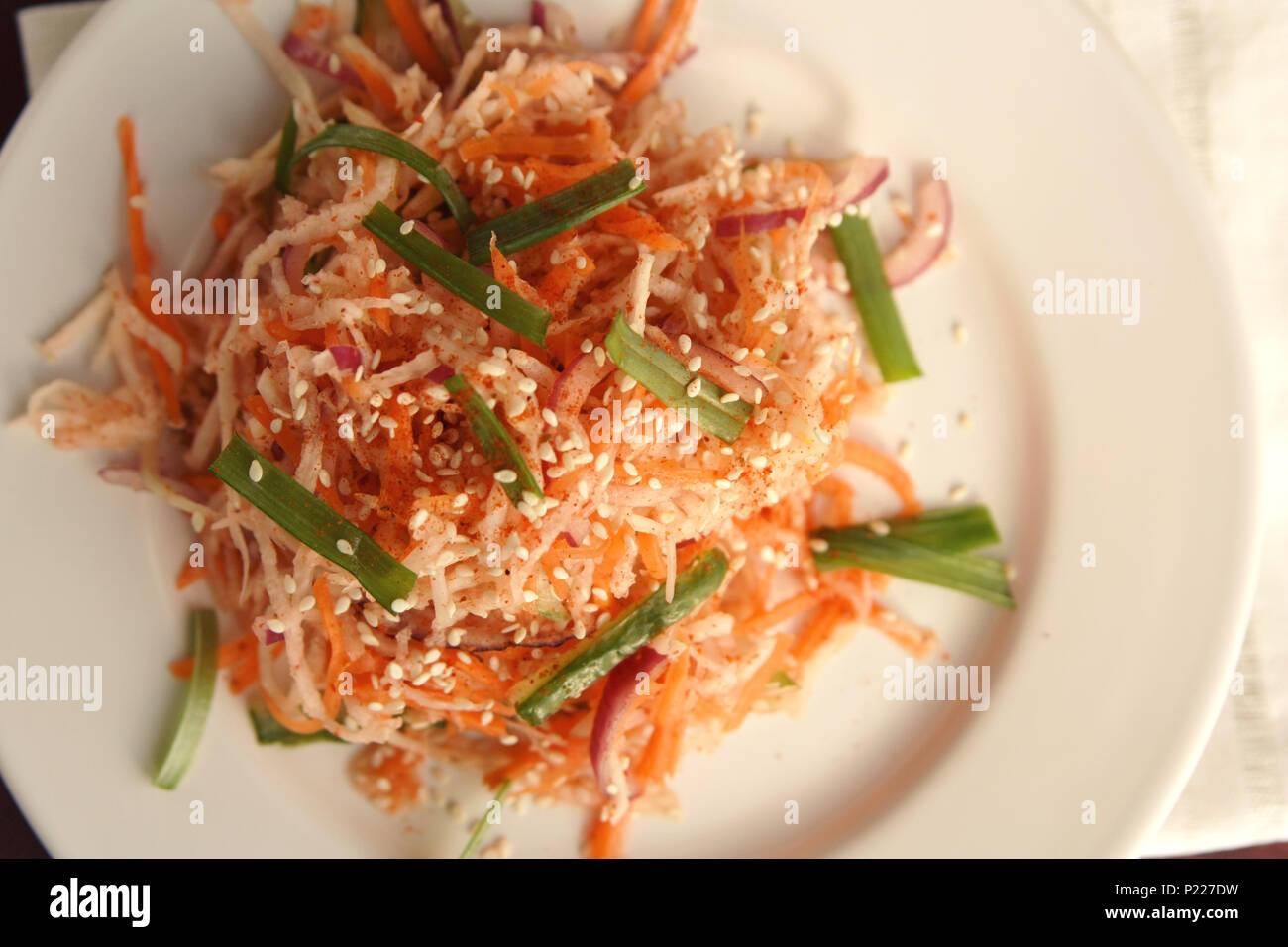 Vegan salad with carrot and radish. Asian cuisine. Healthy vegetarian appetizer on the round plate. Side dish. Simple low calories lunch. Top view. Stock Photo