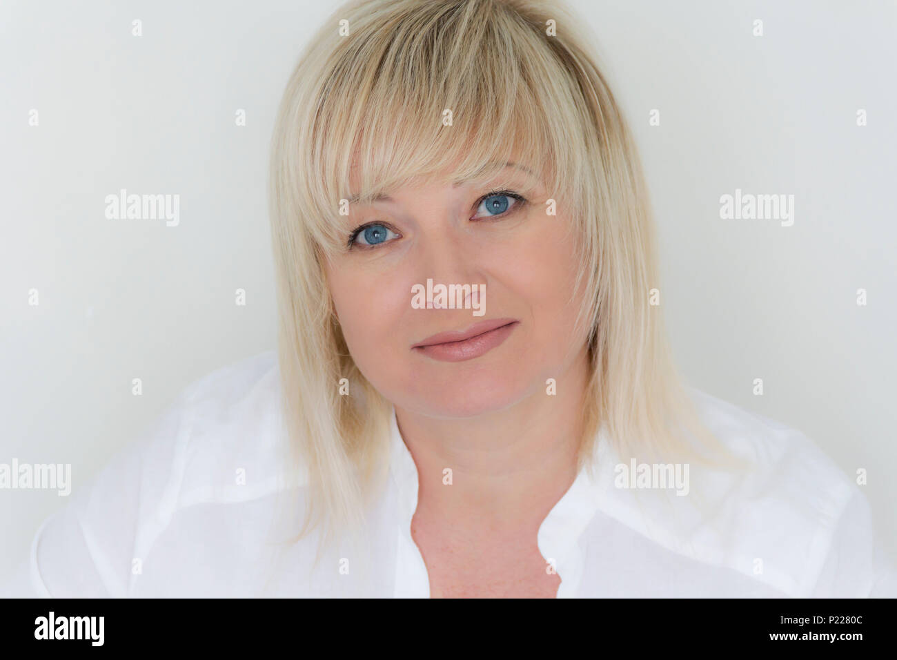 Horizontal portrait of blond woman with blue eyes in white Stock Photo ...