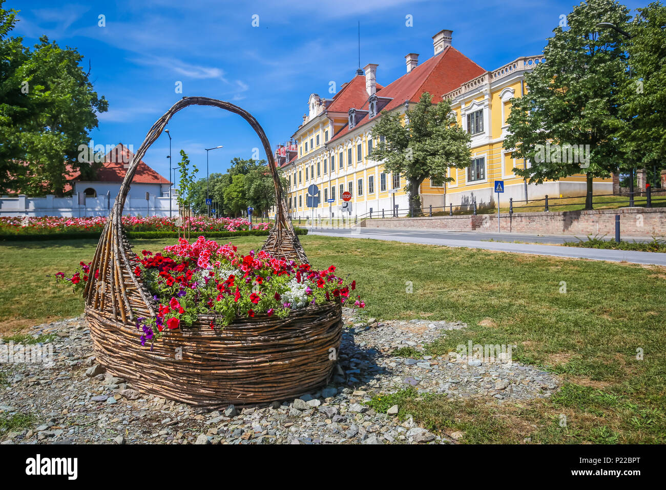 View of a large straw basket with flowers in a park with the City museum located in the Eltz castle in the background  in Vukovar, Croatia. Stock Photo