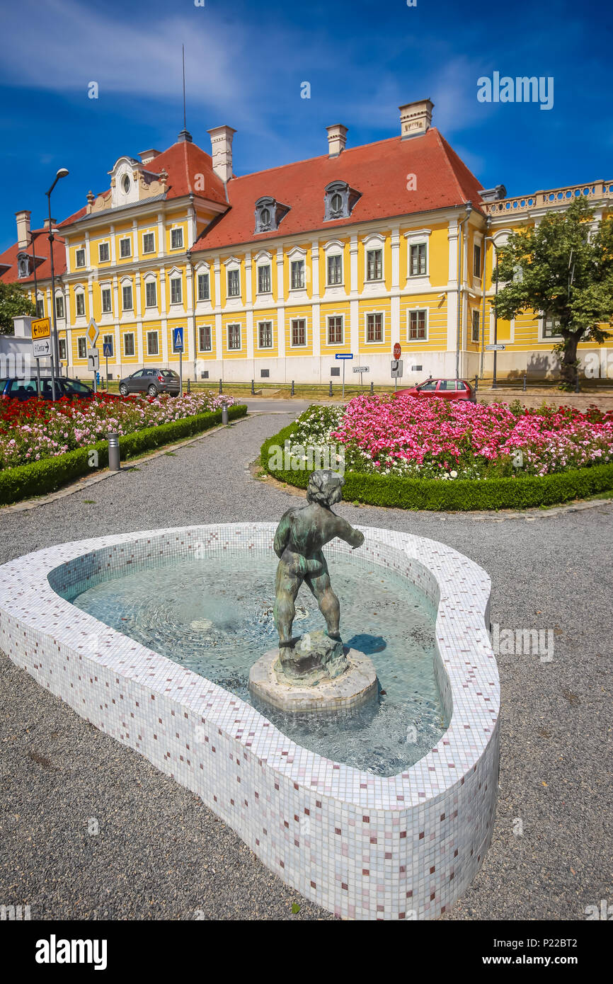 VUKOVAR, CROATIA - MAY 14, 2018 : View of a water fountain with statue and flowers in a park with the City museum located in the Eltz castle in the ba Stock Photo