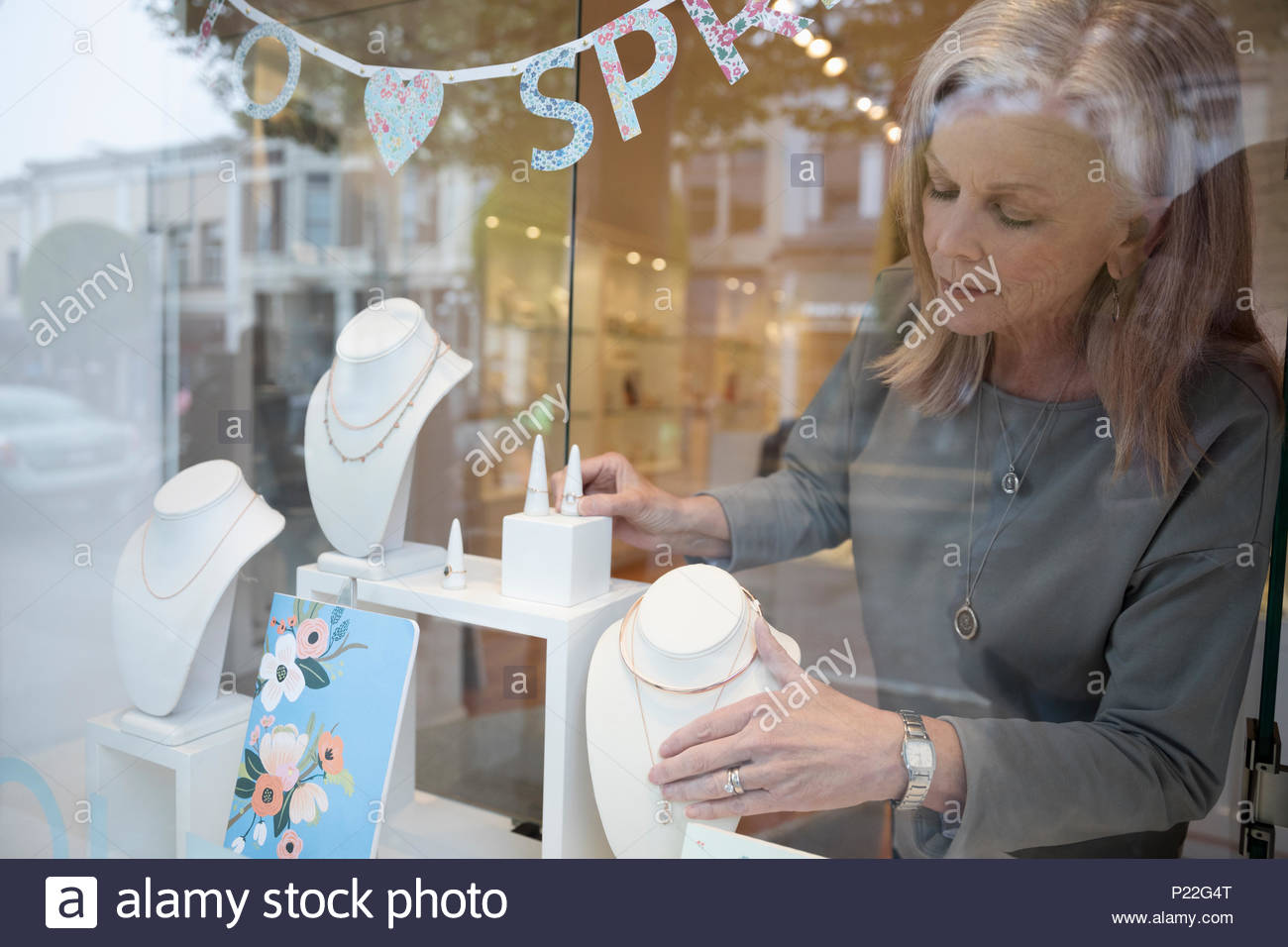 Senior jewelry boutique owner arranging window display Stock Photo
