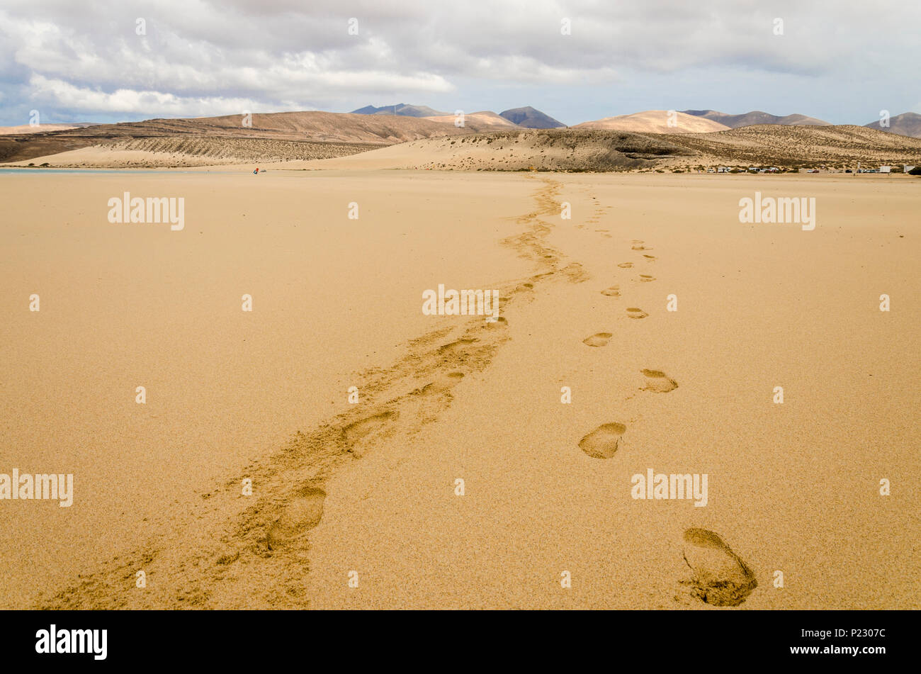 Footprints on the sandy beach of Sotavento, Fuerteventura, Canary Islands with a mountain range and stormy sky Stock Photo