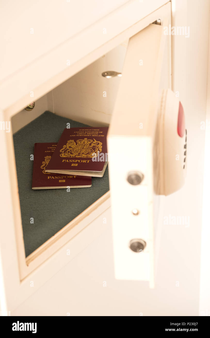 Two passports inside an open hotel room safe or strongbox. The safe has a keypad and an extra thick door for security. Its hidden in a  wardrobe Stock Photo