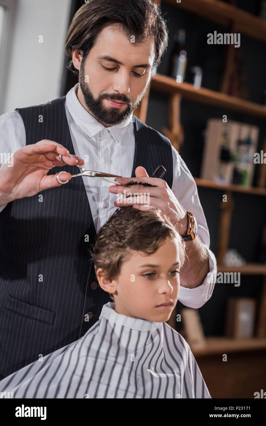 Curly Little Kid Getting Haircut At Kids Barbershop Stock Photo