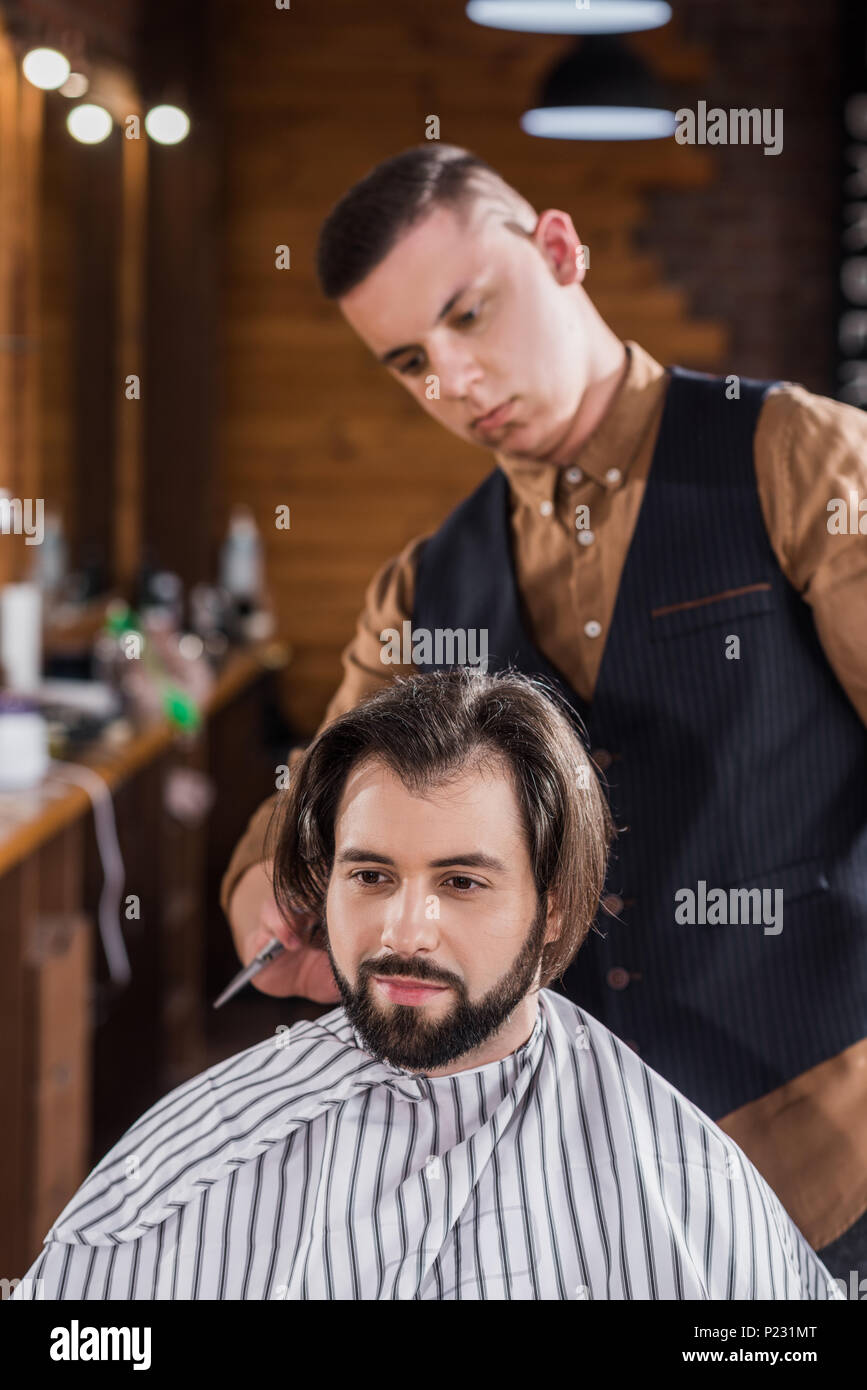 Bearded Young Man Getting Haircut From Professional Barber At