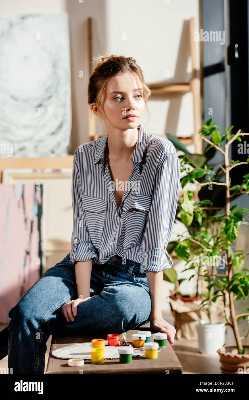 young female artist sitting on bench with paints and looking away Stock ...