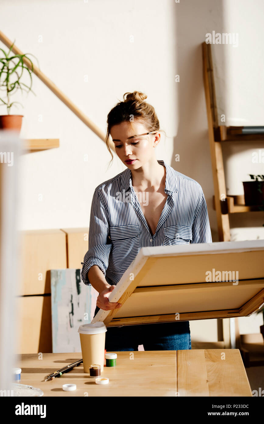 young female artist with canvas in hands in art studio Stock Photo - Alamy