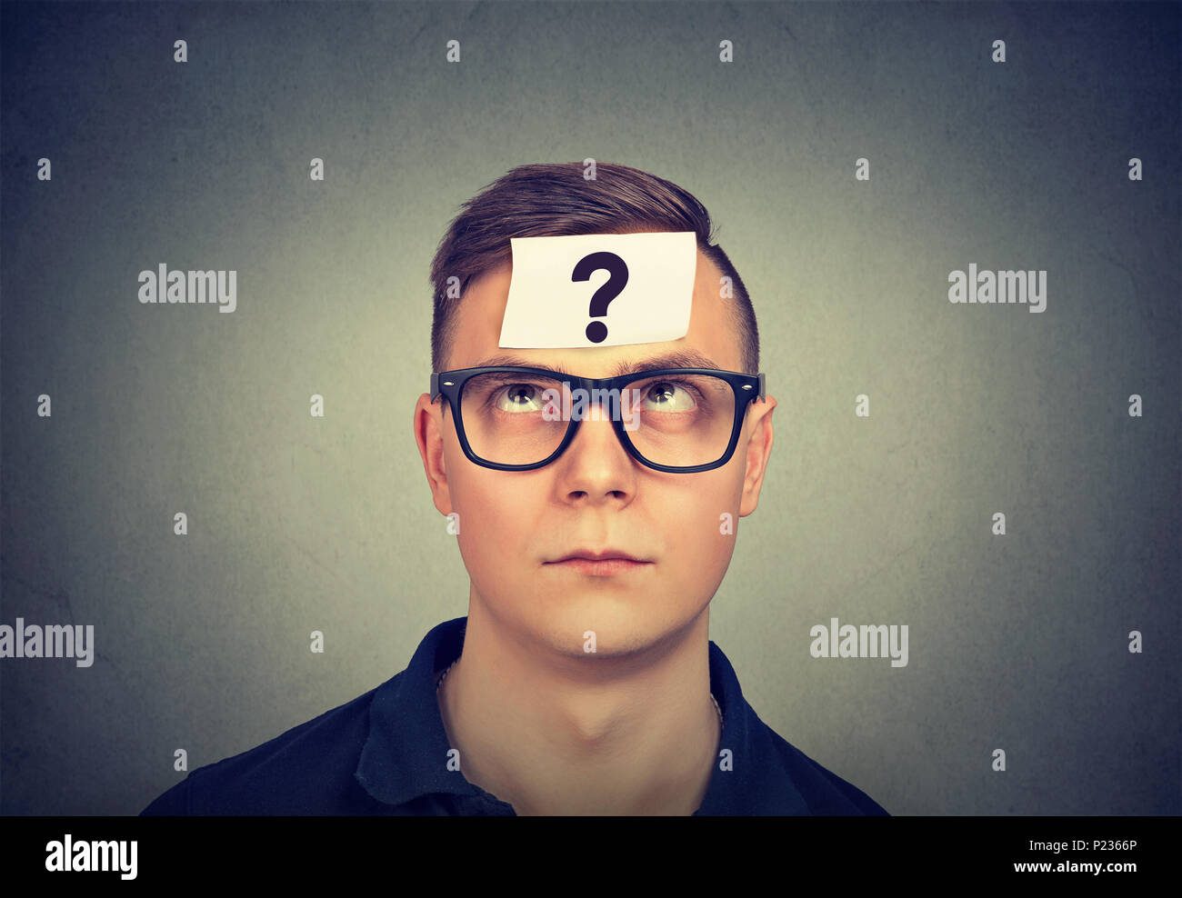 thinking man with question mark on gray wall background Stock Photo