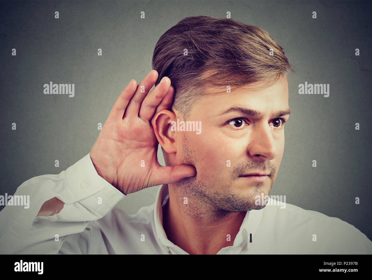 Young man holding hand at ear concentrated on eavesdropping curious about gossip. Stock Photo