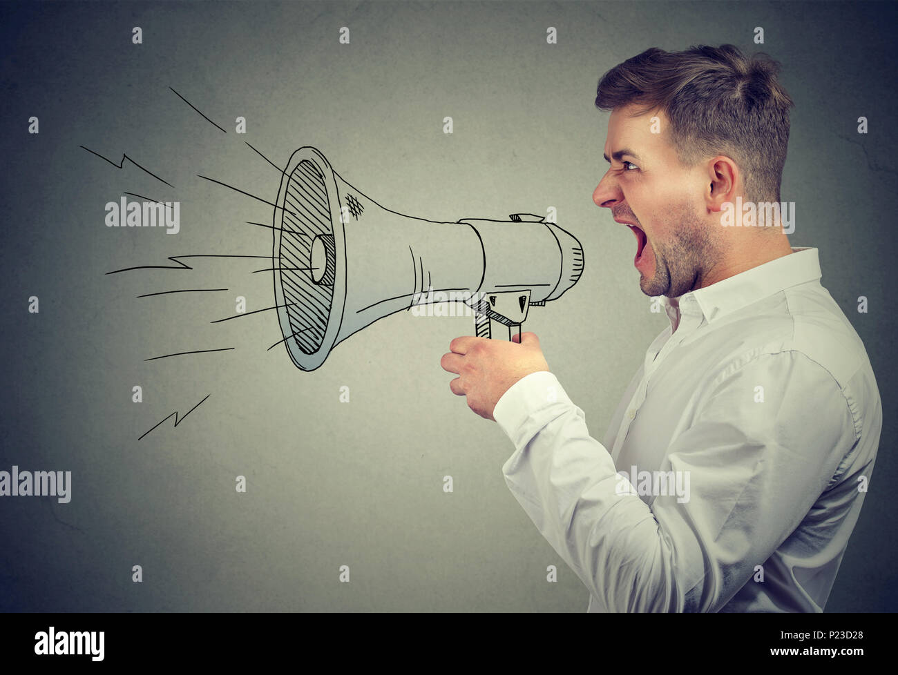 Young anxious man shouting with anger posing with painted loudspeaker. Stock Photo