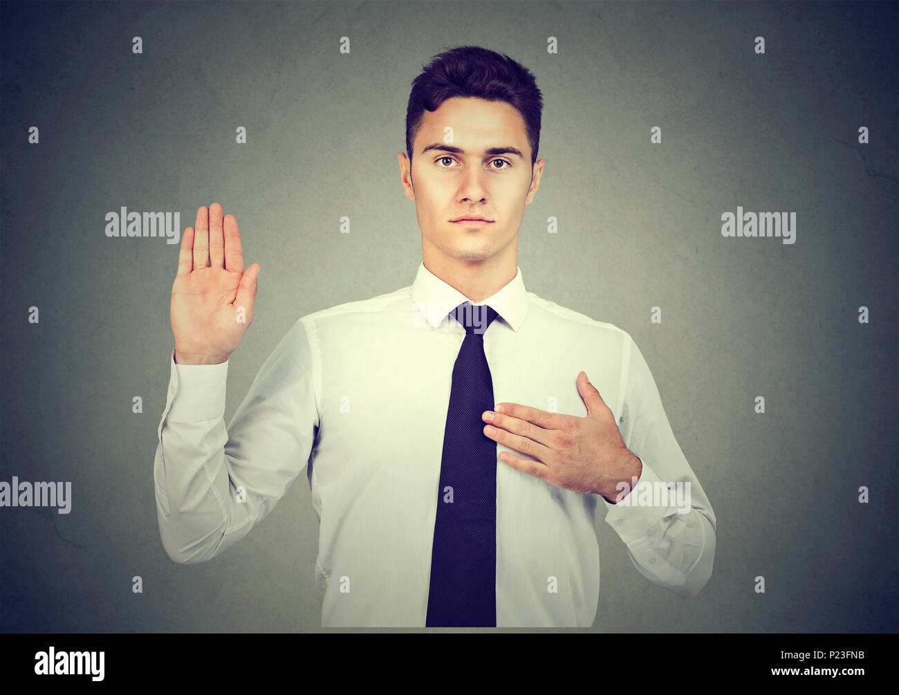 Handsome business man making an oath promise on gray background Stock Photo