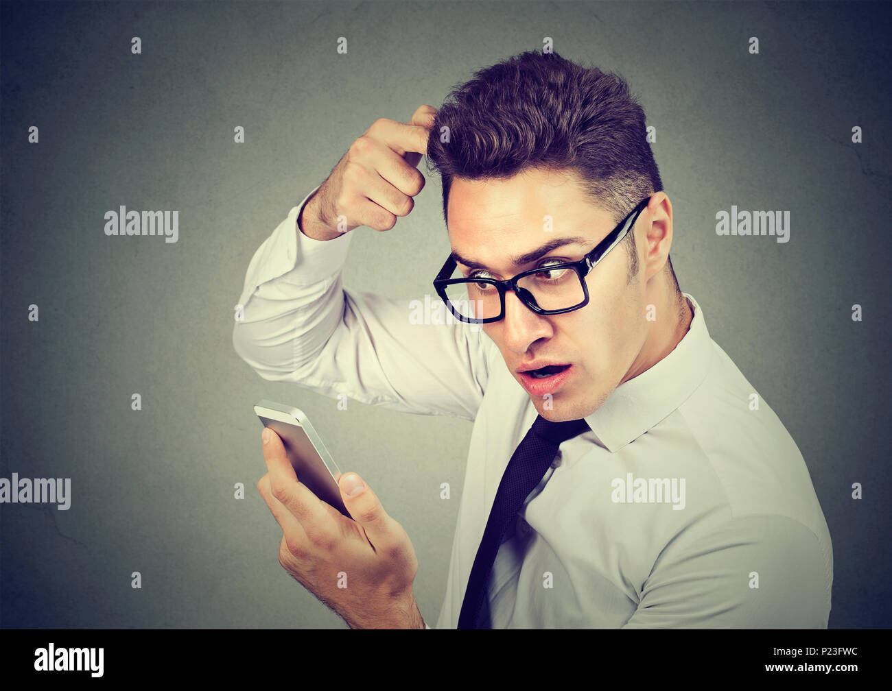 Shocked man feeling head, surprised he is losing hair, receding hairline isolated on gray background. Stock Photo