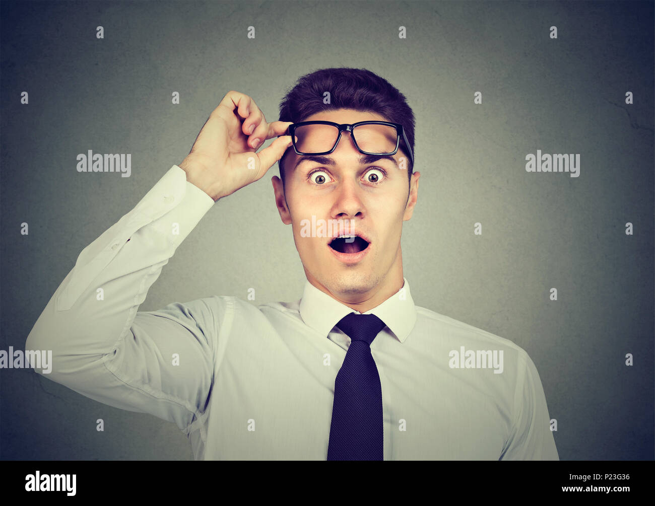 Wow! Surprised young handsome man with opened mouth taking off glasses Stock Photo