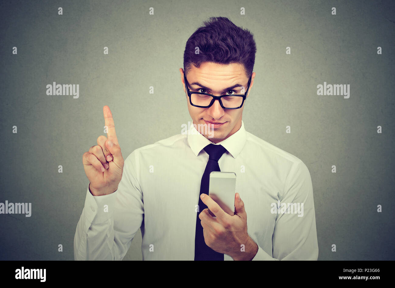 Business man with smartphone showing no, attention with finger hand gesture. Blocking dangerous adult contents. Parental control concept Stock Photo
